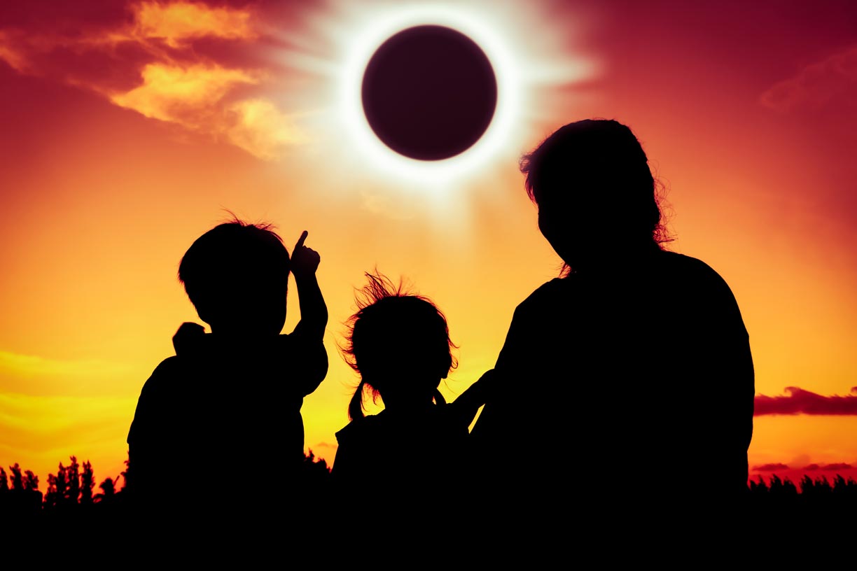 Family watching 2024 total solar eclipse, boy pointing toward sun.